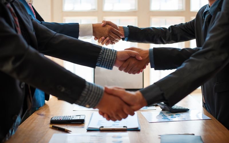Business people shaking hands across a meeting table