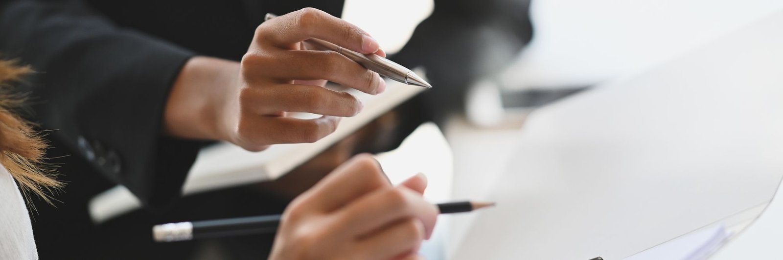Two colleagues working through documents together, pens in hand