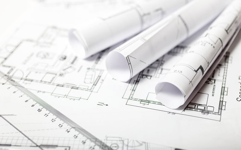 Rolled engineering blueprints on a technical drawing